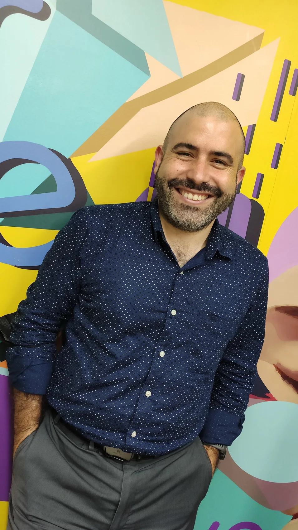 Juan Pablo Neira Vesga, sonriendo frente a un mural de colores